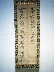 緑の模様が入った枠に漢字文字が書かれている真盛上人念仏志趣書の掛け軸の写真