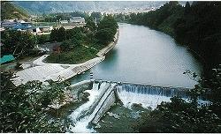 山間を流れる静かな川から滝のように水が流れ落ちている立梅井堰の写真