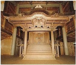 手前に段差があり奥に扉がある木造の新しく再建された千尋江神社本殿の写真