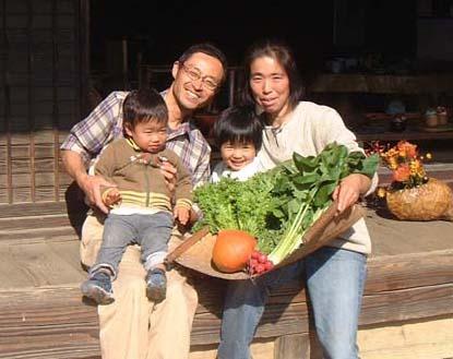 野菜の入ったかごを抱えて笑顔の小島さんご家族の写真