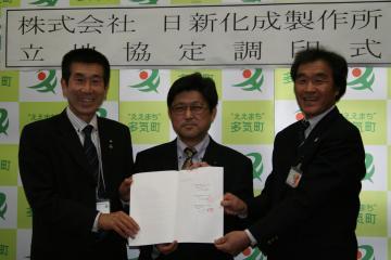 町長と日新化成製作所の代表の方3名で締結書を持って記念撮影をしている写真