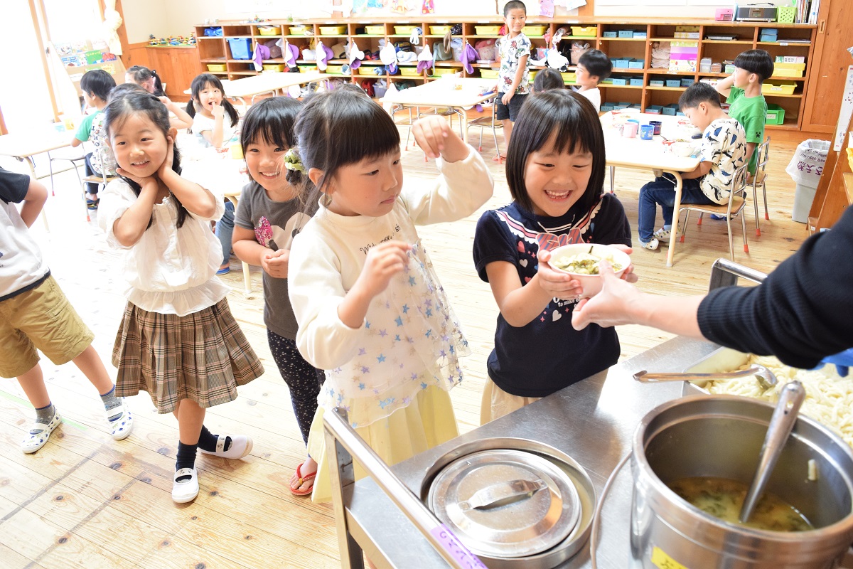 笑顔で嬉しそうに給食を食べている園児たちの写真