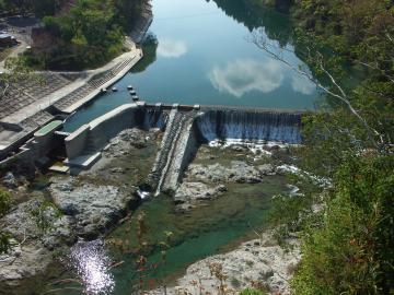 山の中を流れる大きな川に作られた立梅用水井堰の写真