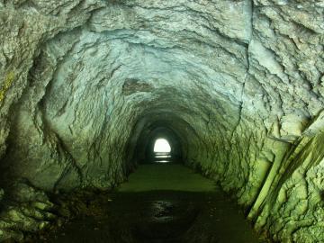 ごつごつとした岩の中に彫られた細いトンネルの写真