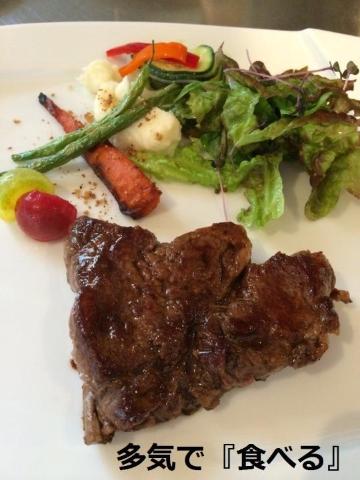 多気で食べるの文字と白いお皿の上にサラダと三角にカットされたステーキが盛りつけられている写真