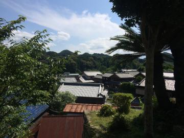 高い場所から見える青空の下の家並みと奥には山々が連なっている写真