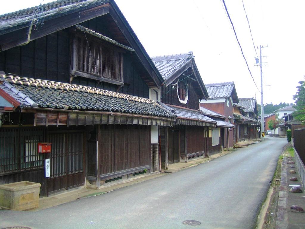 茶色の木造で三角屋根の古い建物が道路の左側に並んでいる和歌山別街道沿いのまち並みの写真